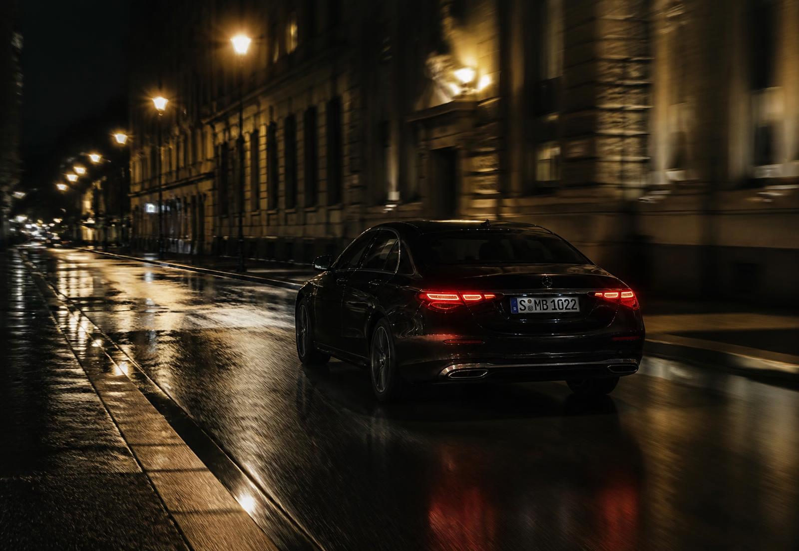 A dark sedan moving through a quiet city street at night